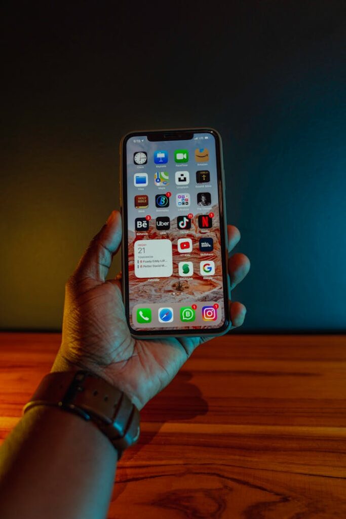 A hand holding a smartphone displaying app icons, with a modern minimalistic background.