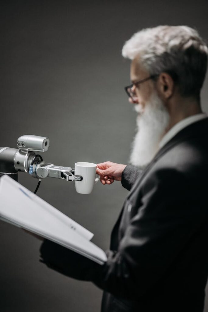 Elderly man interacts with robot arm holding a cup, showcasing innovation indoors.